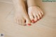 A woman's feet with red nail polish on a wooden floor.