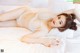 A woman laying on a bed in a white lingerie.
