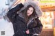 A woman in a black jacket is standing in the snow.