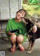 A woman sitting on the ground with a dog and a bowl of food.