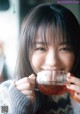 A young woman holding a cup of tea in her hand.