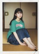 A young woman sitting on the floor wearing a green shirt.