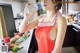 A woman in a red dress drinking water from a bottle.