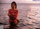 A woman in a red dress standing in the water.