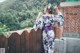 A woman in a kimono standing on a wooden fence.