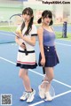 Two young women standing on a tennis court holding tennis rackets.