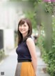 A woman in a blue top and yellow skirt posing for a picture.