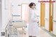 A woman in a white lab coat standing in a hospital hallway.