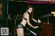 A woman in a black lingerie playing a piano.